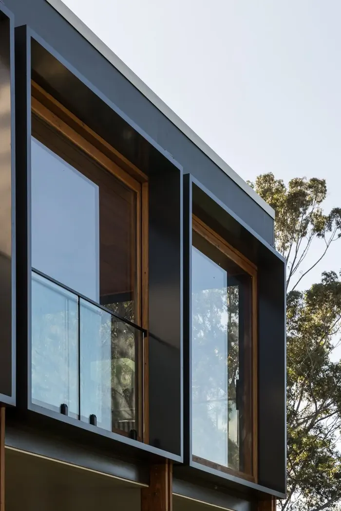 Dark window frames set into timber reveals with a glass balustrade, Coledale renovation detail