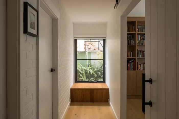 Hallway with a built-in timber window seat and recessed bookshelf joinery, Coledale
