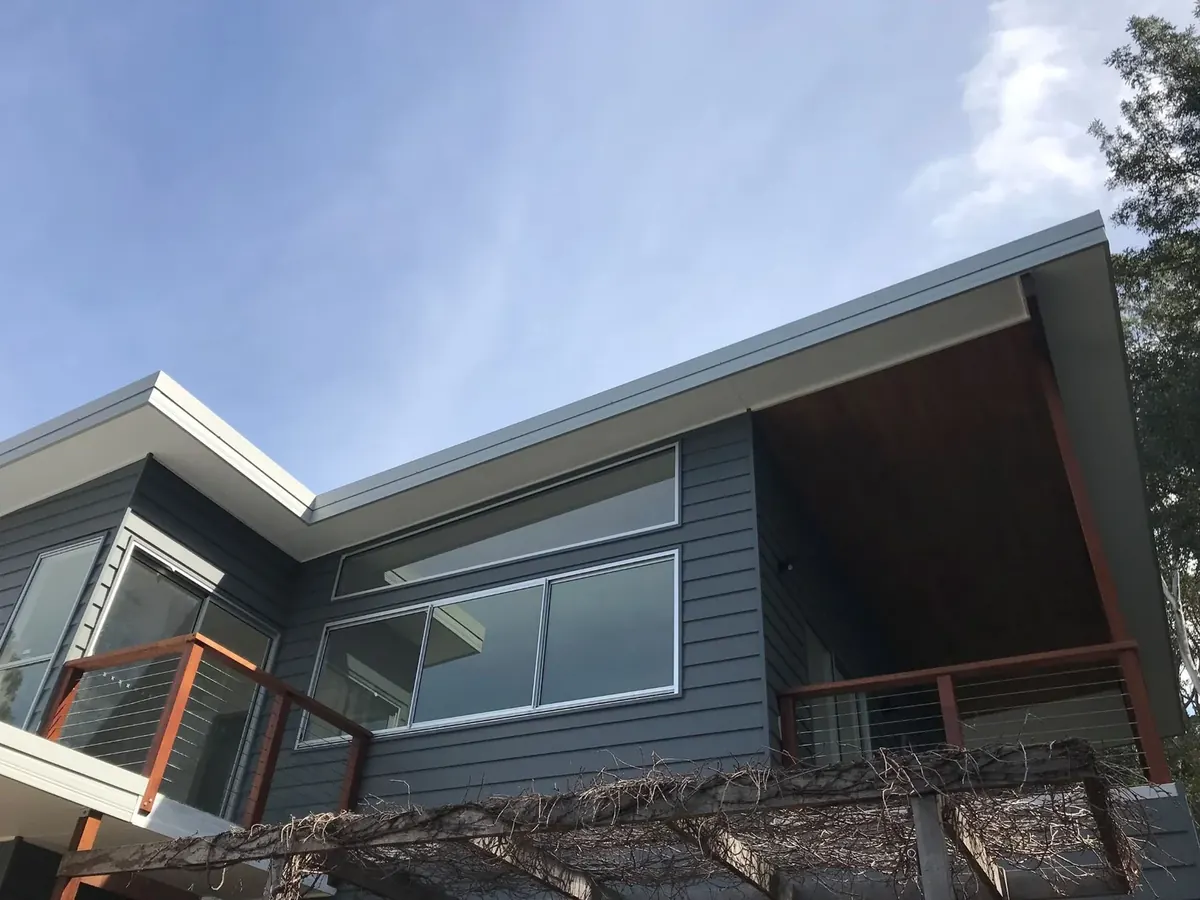 Second-storey addition with weatherboard cladding and a skillion roof on a steep coastal block in Wombarra, built by CKS Projects